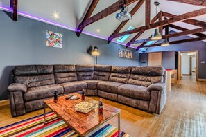 A modern living room with a large sectional sofa, a wooden coffee table, and a colorful striped rug. - 5 Bed in Holsworthy (oc-60490) (Clawton)