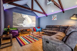 Ein modernes Wohnzimmer mit freiliegenden Holzbalken, einem großen abstrakten Gemälde, einem gemütlichen Sofa, einem Couchtisch und einem farbenfrohen Streifen Teppich.