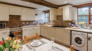 Une cuisine avec des meubles blancs, un four à micro-ondes, un grille-pain, un évier et un lave-linge.