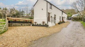Un bâtiment blanc avec une allée gravillonnée et une clôture en bois.