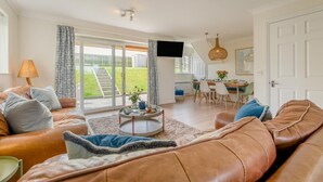 Uma sala de estar espaçosa com um sofá, uma mesa de centro e um espaço de jantar com cadeiras e uma mesa.
