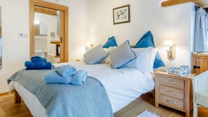 Una camera da letto ordinata con un letto, comodini, una sedia e uno specchio.