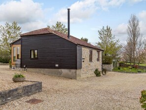 Un bâtiment à l’extérieur sombre, doté d’une cheminée et d’une allée gravillonnée.