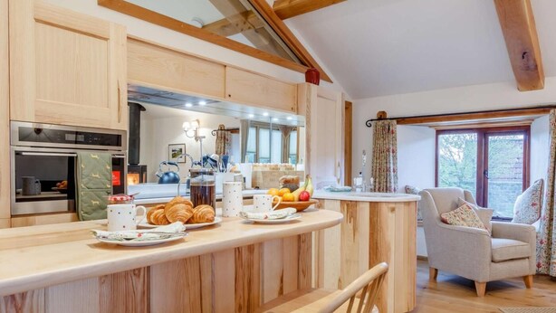 Una cucina con mobili in legno, un'isola centrale e un'area pranzo con una sedia e un tavolo.