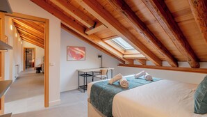 A bedroom with a skylight, a desk, and a bed with towels. - Welcomer La Latina (Madrid)