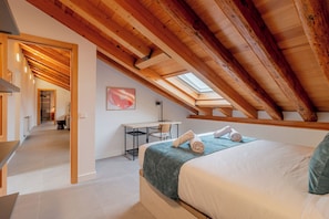 Un dormitorio con tragaluz, un escritorio y una cama con toallas.