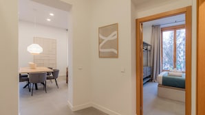 A modern interior with a dining area, a hallway leading to a bedroom, and a view of the outside. - Welcomer La Latina (Madrid)