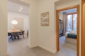 Un interior moderno con comedor, un pasillo que lleva a un dormitorio y vistas al exterior.