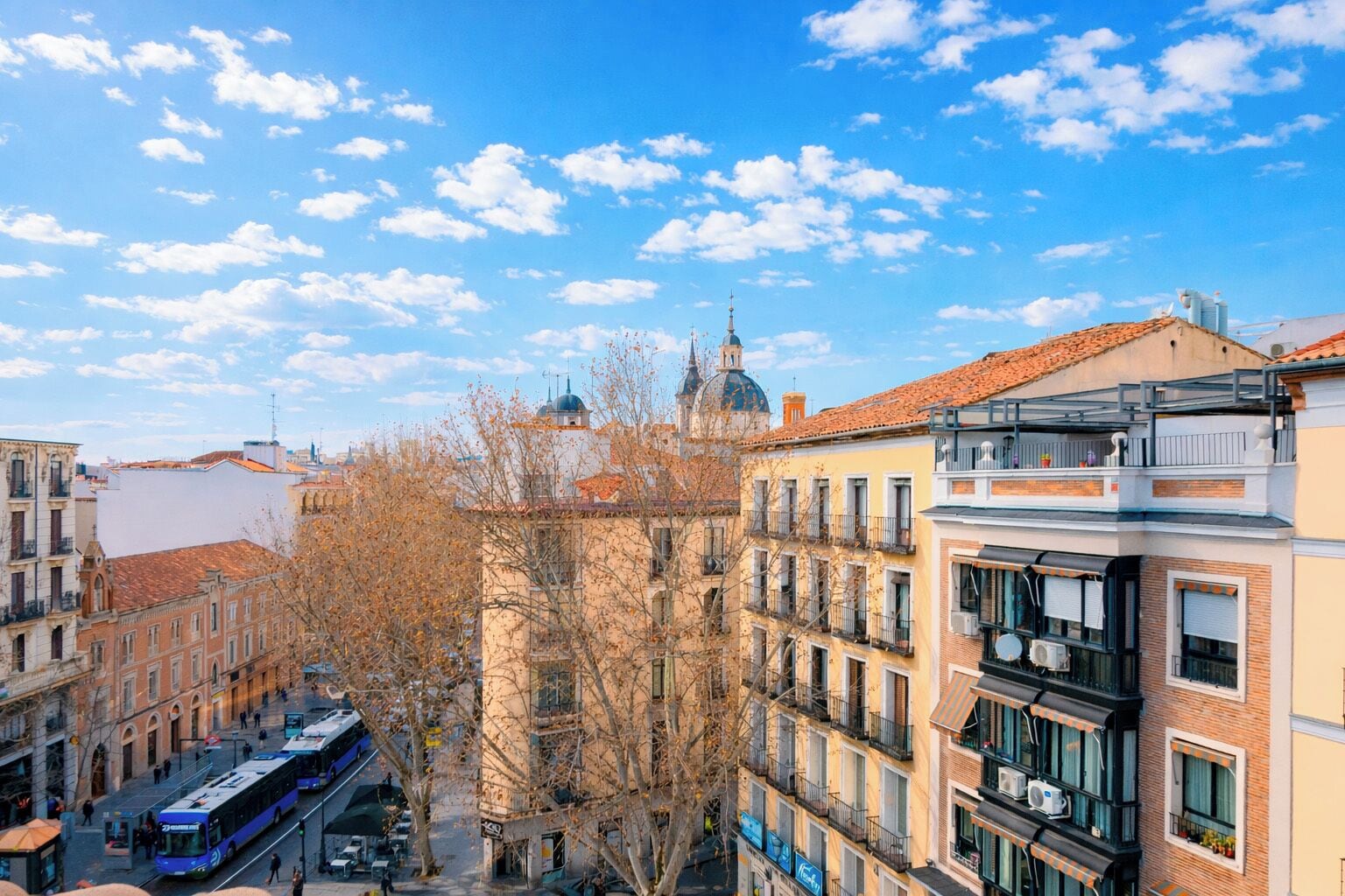 A cityscape with multi-story buildings, a tram, and a clear sky.