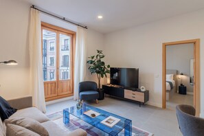 Un salon moderne avec un canapé, une table basse, un téléviseur et une plante en pot.