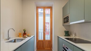 A compact kitchen with a sink, stove, and microwave. - Welcomer La Latina (Madrid)