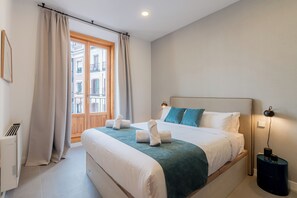 Une chambre d’hôtel avec un grand lit, une fenêtre avec des rideaux, une table de chevet avec une lampe et un radiateur.
