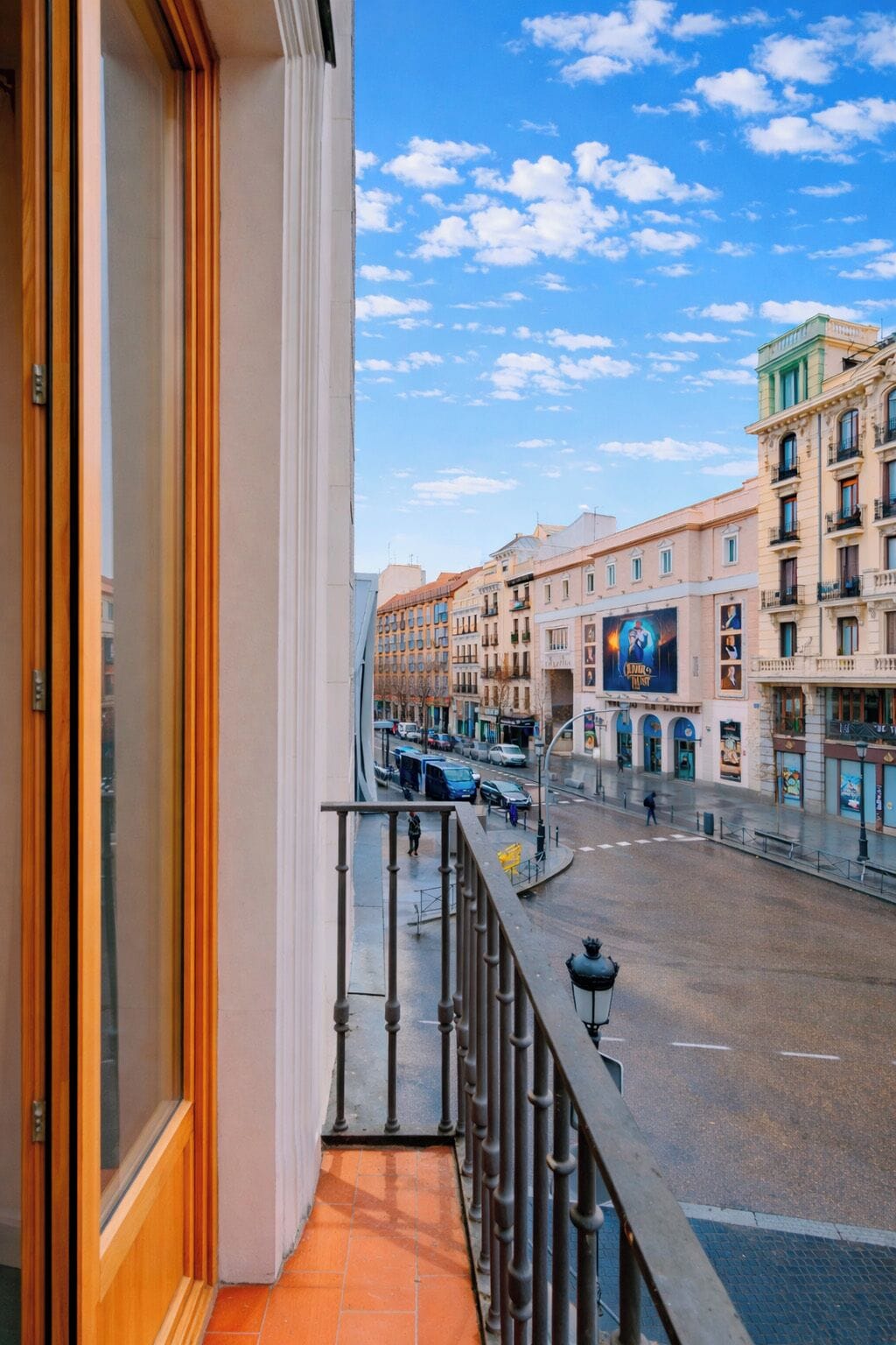 Un balcon donnant sur une rue de la ville, avec vue sur les immeubles et un ciel dégagé.