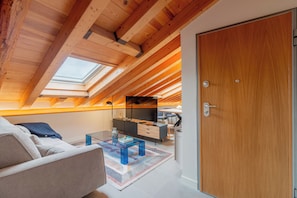 A loft-style room with a sloped ceiling, a skylight, a sofa, a coffee table, and a desk with a chair. - Welcomer La Latina (Madrid)