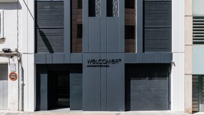 Un edificio moderno con un letrero que dice 'WELCOME', una puerta de garaje y un cartel de 'prohibido estacionar'.