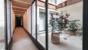 Un pasillo moderno con paredes de vidrio, techo de madera y plantas en macetas.
