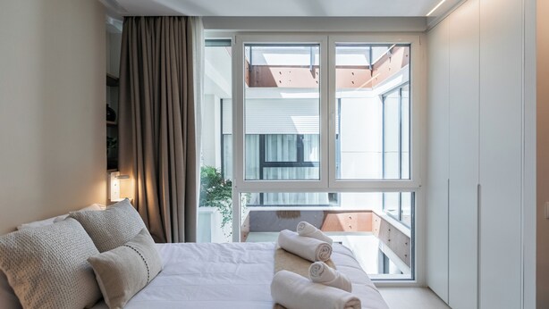 Habitación de hotel con cama, cortinas, ventana y balcón.
