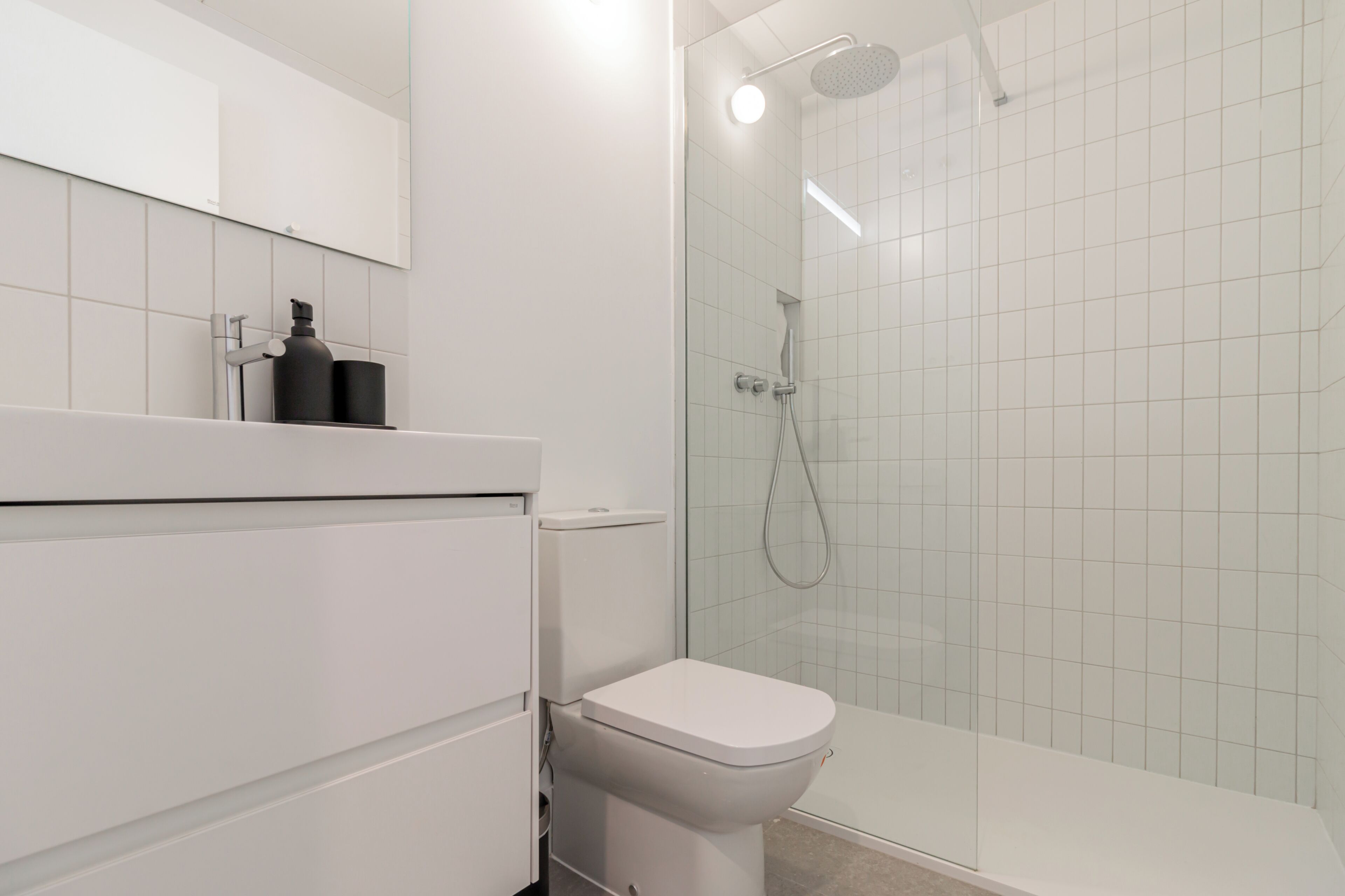 A modern bathroom with a toilet, a shower, and a sink.