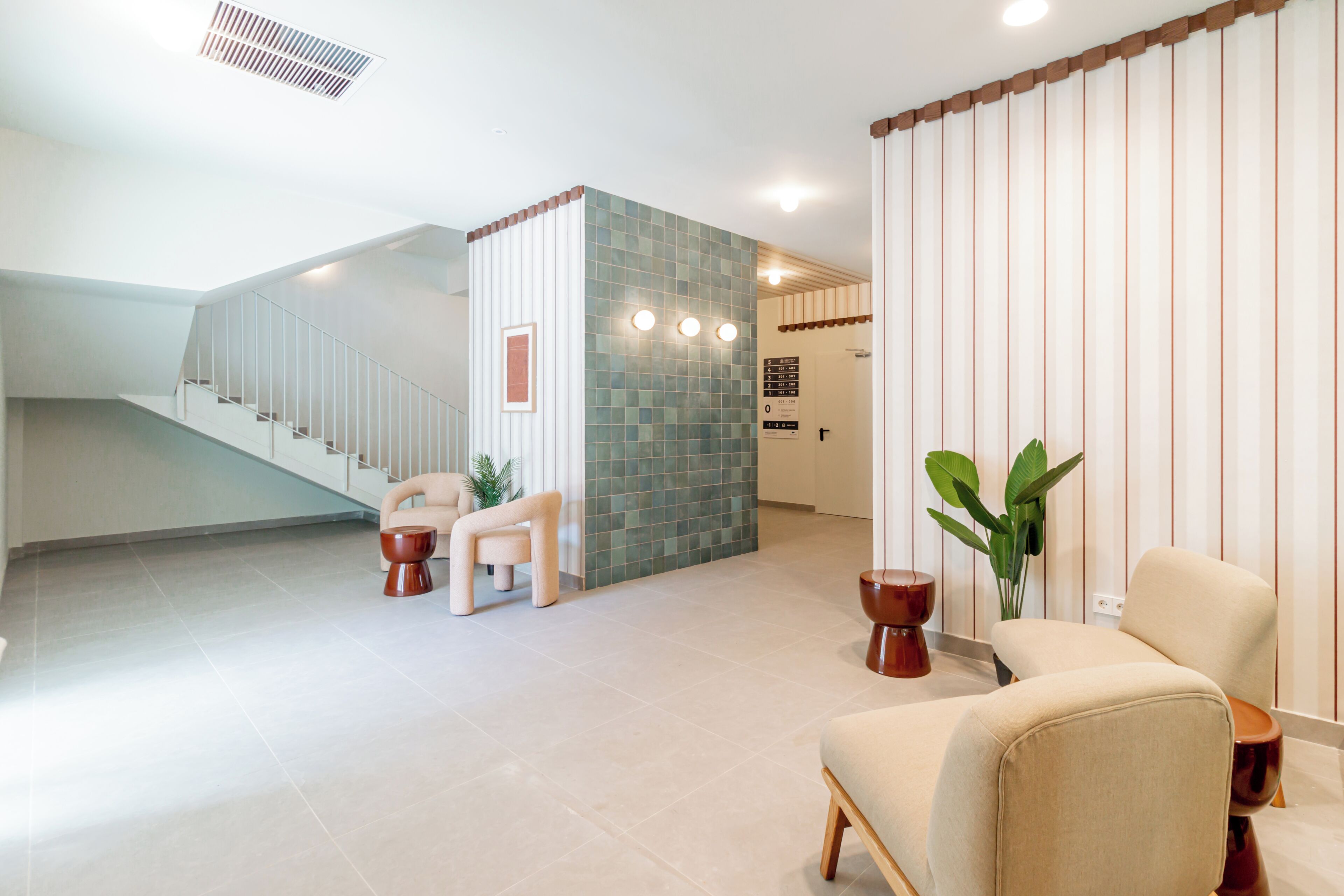 A spacious lobby with a staircase, a seating area, and a decorative wall.