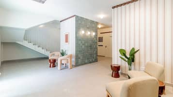 A spacious lobby with a staircase, a seating area, and a decorative wall.