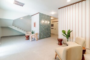 Um hall amplo com escada, área de estar e parede decorativa.