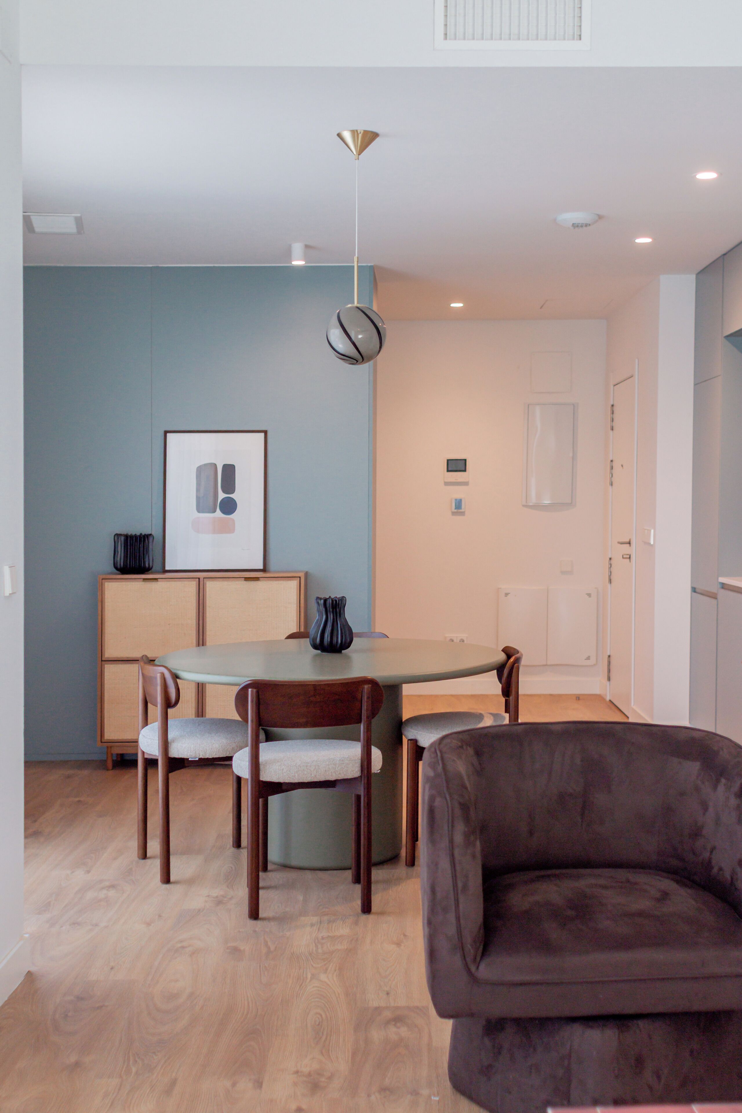 A modern dining area with a table, chairs, a sofa, and a pendant light.