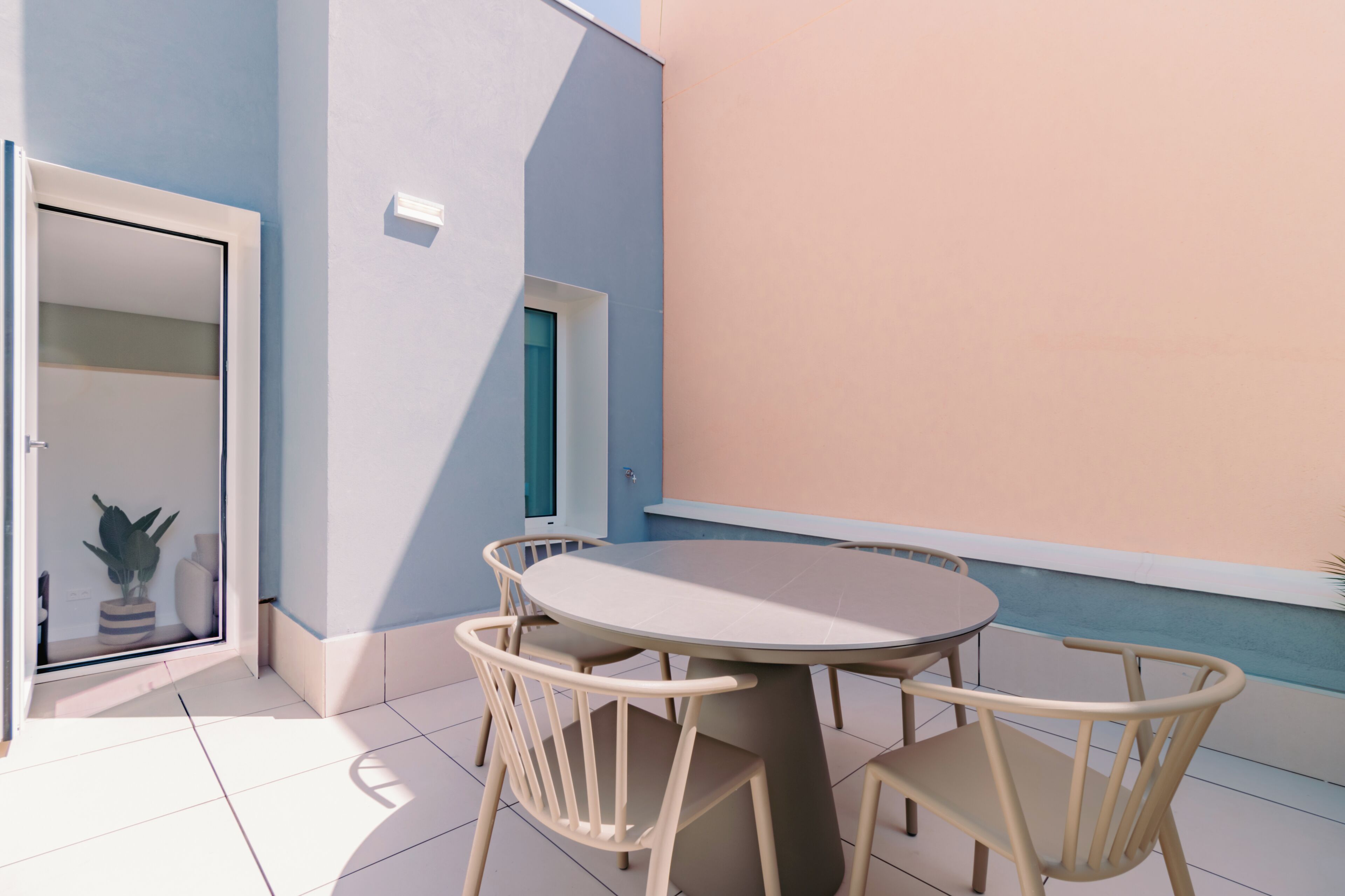 Une table ronde avec quatre chaises, une porte et une fenêtre donnant sur le ciel.