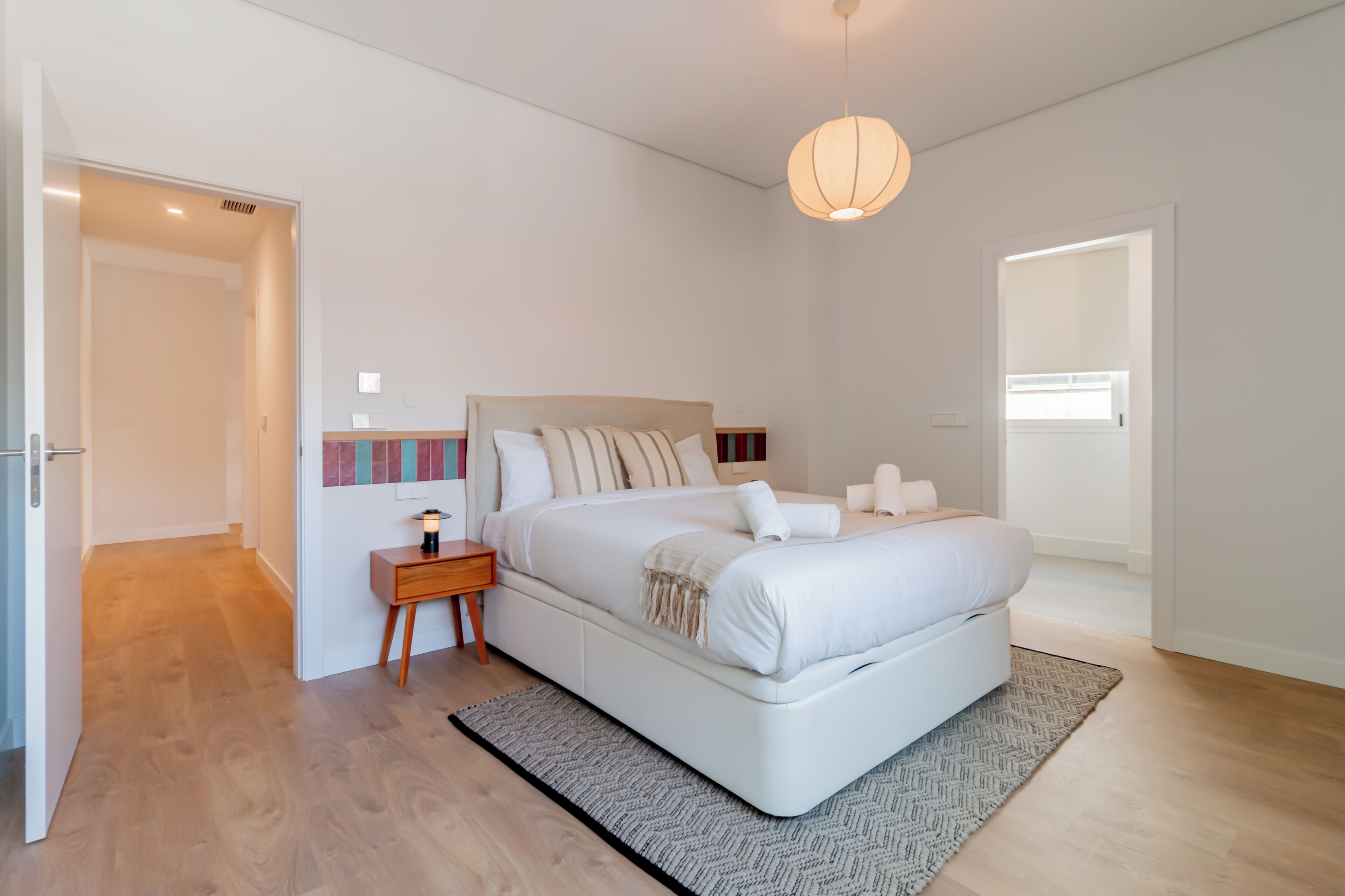 Un dormitorio moderno con una cama grande, mesitas de noche y una lámpara colgante.