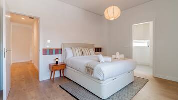 Un dormitorio moderno con una cama grande, mesitas de noche y una lámpara colgante.