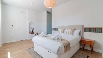 A bedroom with a bed, bedside table, and a hanging light fixture.