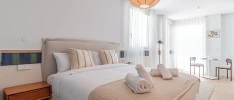 A modern hotel room with a large bed, a bedside table, a lamp, and a view of the room.