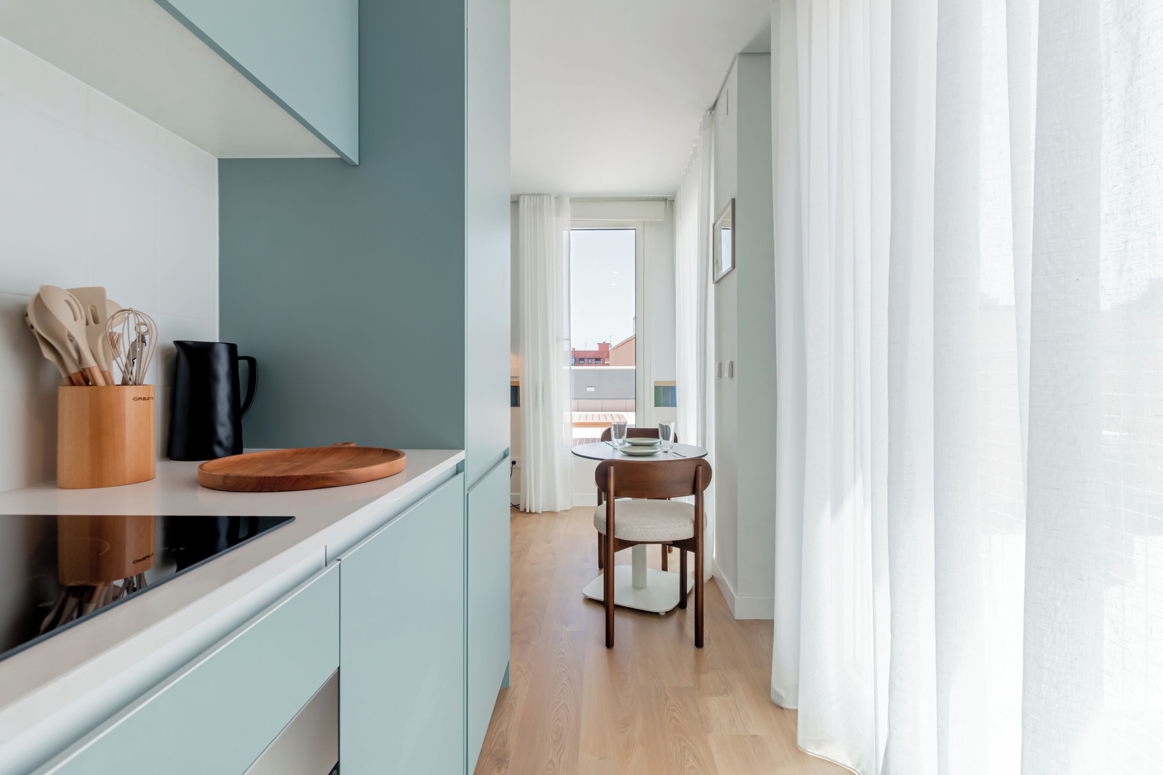 A modern kitchen with a wooden cutting board, a black kettle, and a wooden utensil holder.