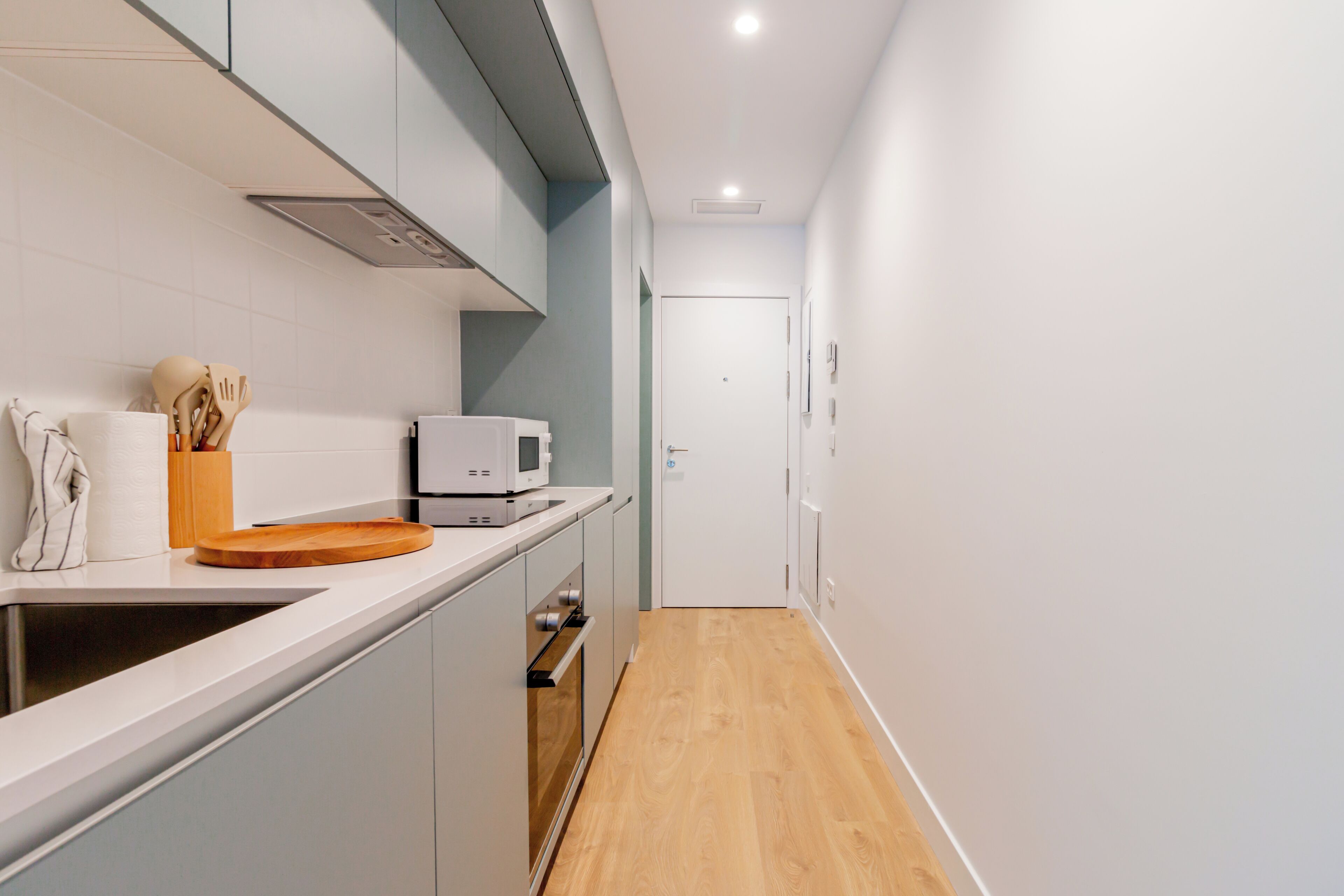A modern kitchen with a microwave, wooden cutting board, and utensils.