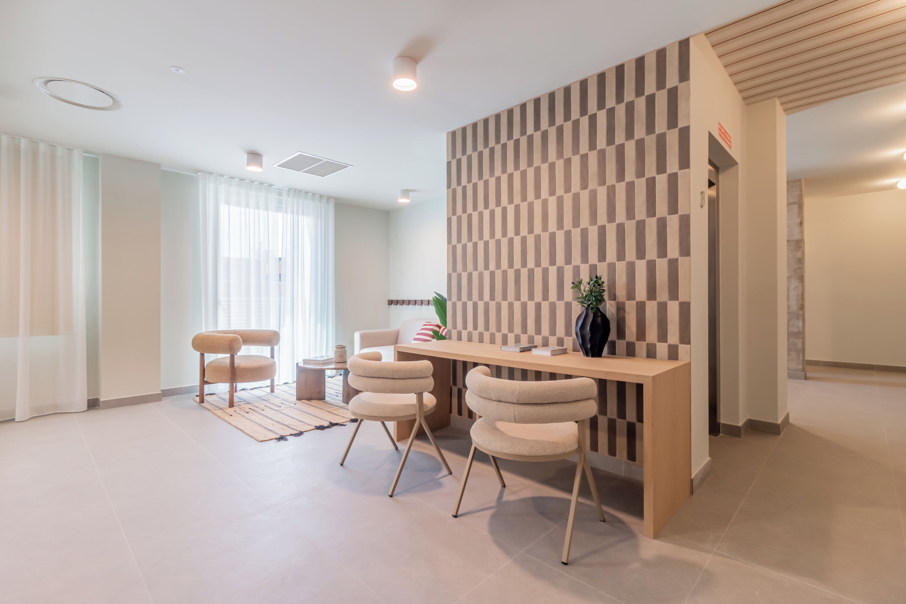 Een moderne receptiebalie met een geruit wandpaneel, een houten toonbank en twee stoelen.