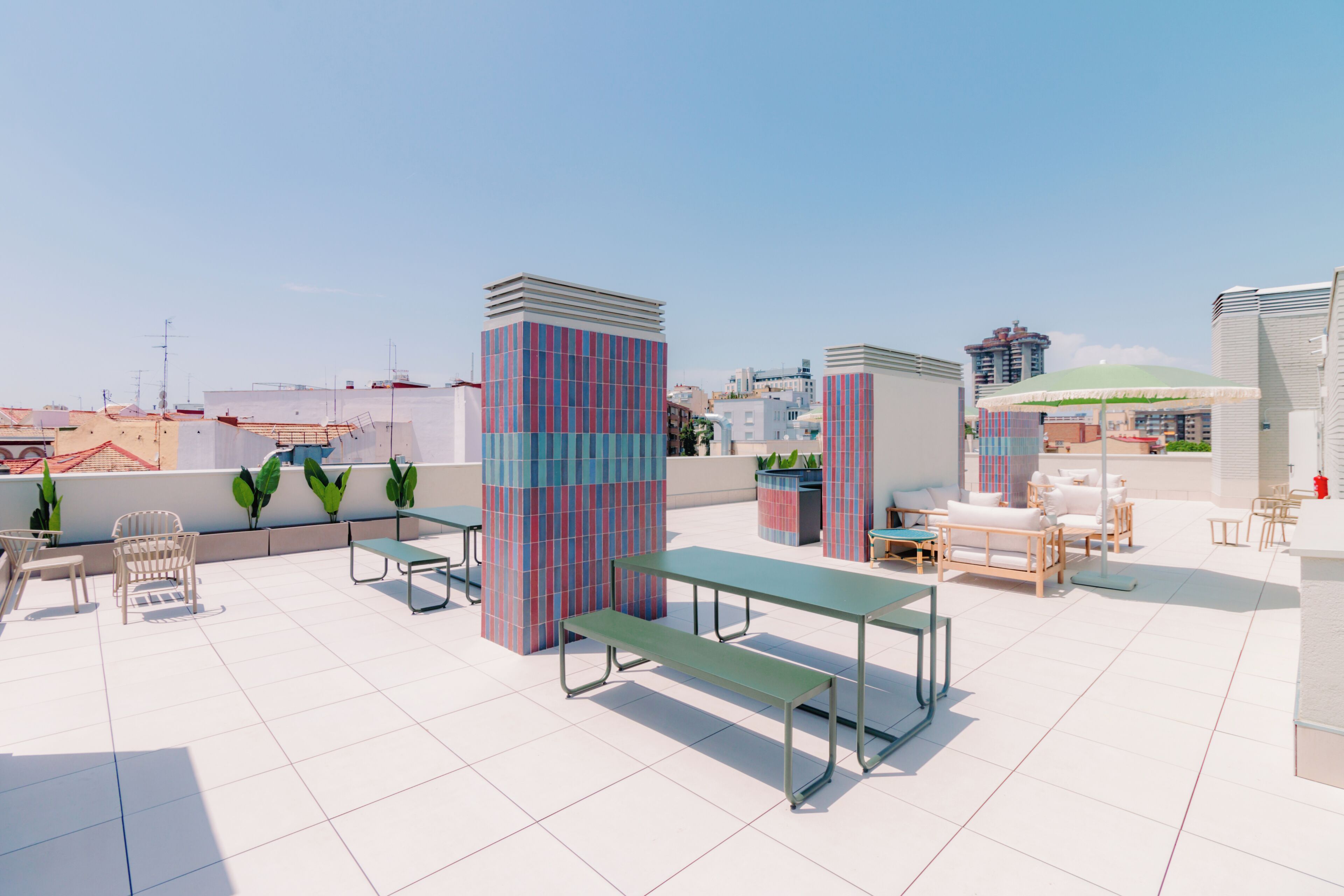 Terraza en la azotea con mobiliario, macetas y vistas a la ciudad.