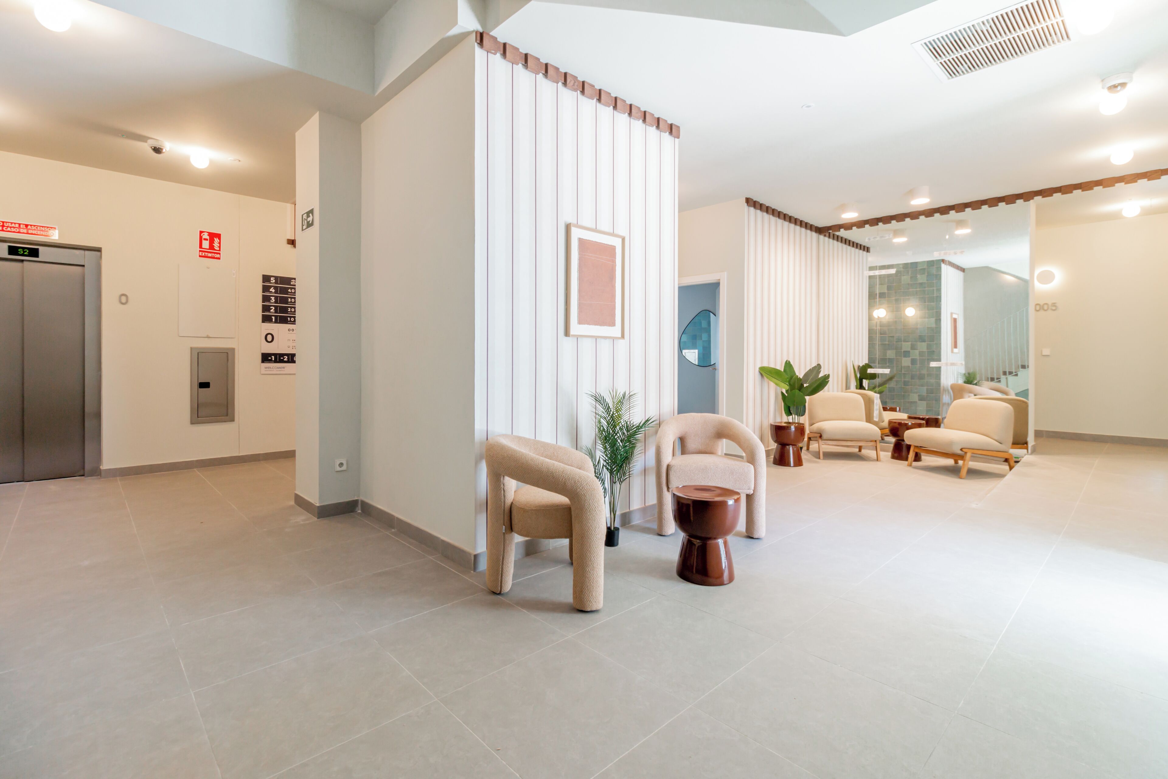 Eine moderne Lobby mit Empfangstresen, Sitzgelegenheiten und einem Aufzug.