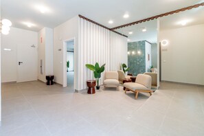 Um quarto espaçoso com design moderno, com área de estar com duas cadeiras, um vaso de plantas e uma pequena mesa.