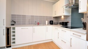Een moderne keuken met witte kastjes, een zwart fornuis en een roestvrijstalen afzuigkap.