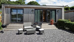 Een modern huis met een terras, meubels van riet en een barbecue.