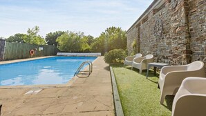 A swimming pool with a stone wall, a lifebuoy, and outdoor chairs. - 2 Bed in Bideford (oc-60428) (Pusehill)