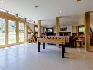 A spacious indoor area with a foosball table, large windows, and a fireplace. - 4 Bed in Gloucester (oc-60200) (Redmarley D'Abitot)