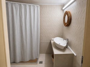 Une salle de bain avec un rideau de douche, un lavabo et un miroir.
