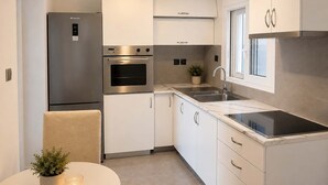 Una cocina moderna con electrodomésticos de acero inoxidable, armarios blancos, horno empotrado y una ventana sobre el fregadero.