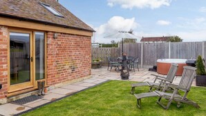 Une maison en briques dotée d’un patio, d’un espace salon extérieur et d’un jacuzzi.