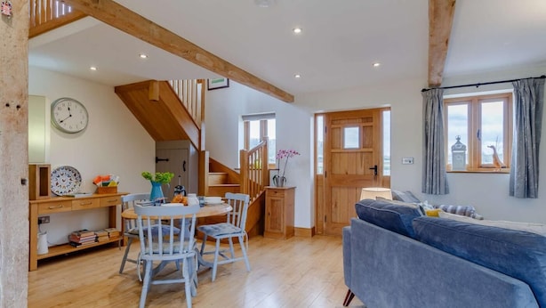 Un vaste espace de vie comprenant un escalier en bois, une table à manger avec des chaises, un canapé et une vue par la fenêtre.