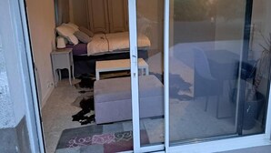 Une pièce comprenant un lit, une petite table, un banc et une porte-fenêtre coulissante donnant sur l’extérieur.