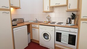 Cocina compacta con lavadora, horno y un lavamanos pequeño.