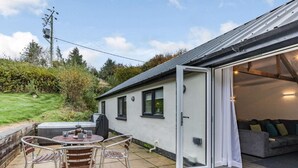 A house with a patio, a hot tub, and a sliding glass door leading to a living area. - 2 Bed in Barnstaple (oc-60443) (Bittadon)
