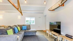 A modern living room with a sectional sofa, a flat-screen TV, wooden beams, and pendant lighting. - 2 Bed in Barnstaple (oc-60443) (Bittadon)