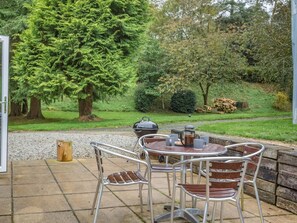 An outdoor patio with a table and chairs, a barbecue grill, and a coffee pot. - 2 Bed in Barnstaple (oc-60443) (Bittadon)